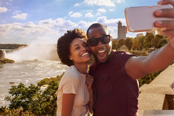 Happy Couple Taking A Selfie In Front Of Niagara Falls